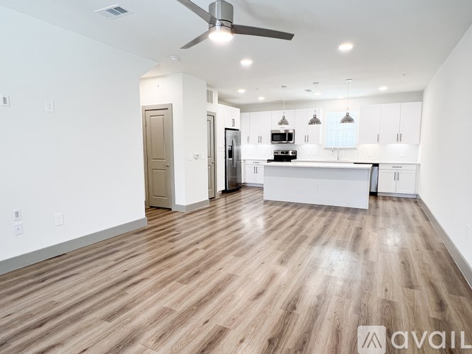 A spacious kitchen with a fan and wooden flooring.