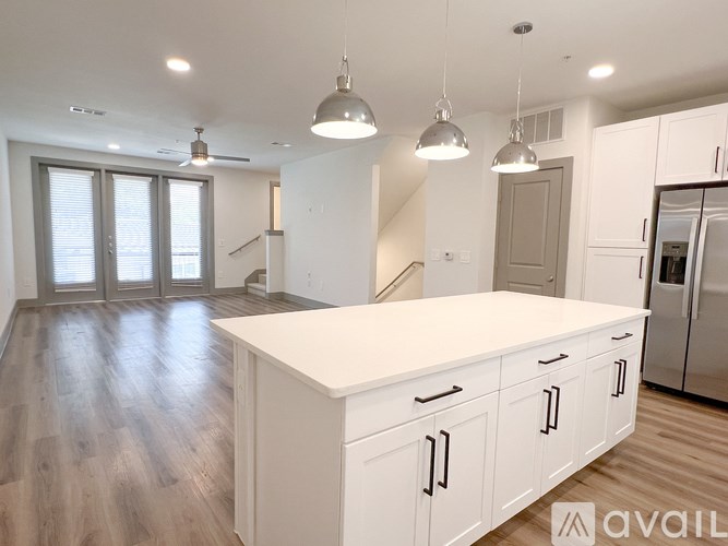 A modern kitchen with white cabinets and a wooden floor.