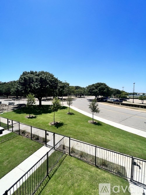 A black fence surrounds a grassy area with trees.
