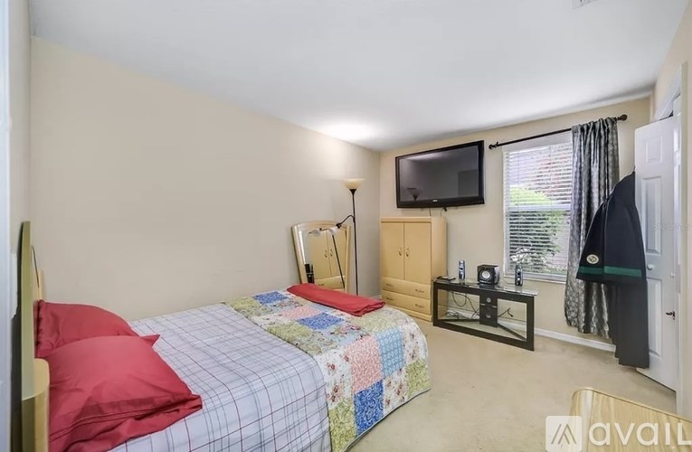 A bedroom with a bed, a chair, a nightstand, and a television.