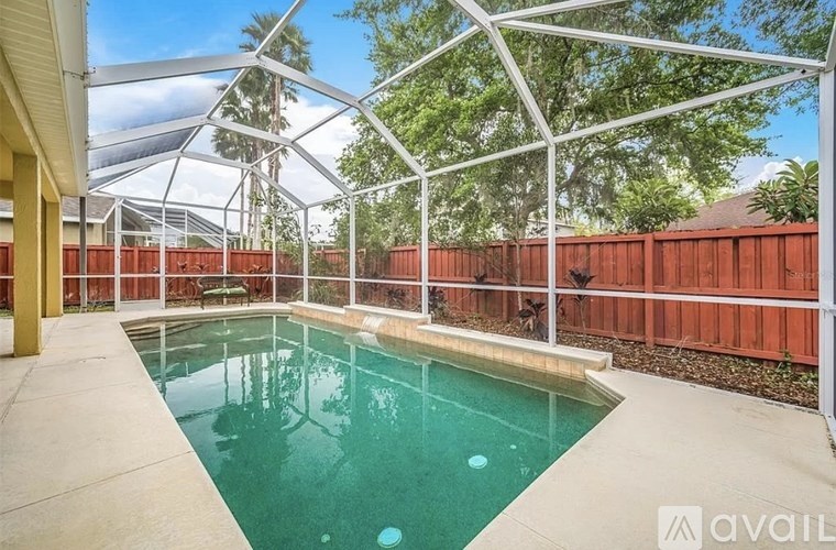 A pool under a white metal structure with a red fence in the background.