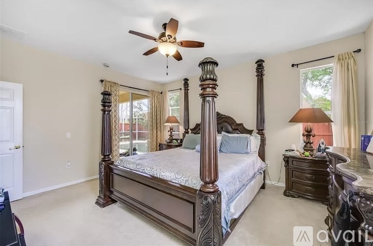 A bedroom with a large bed and a ceiling fan.