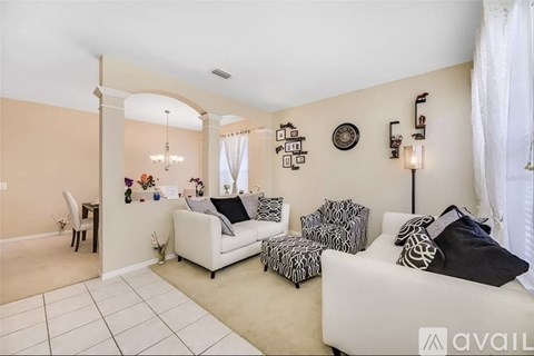 A living room with a white couch, a chair, and a table with a vase of flowers on it.