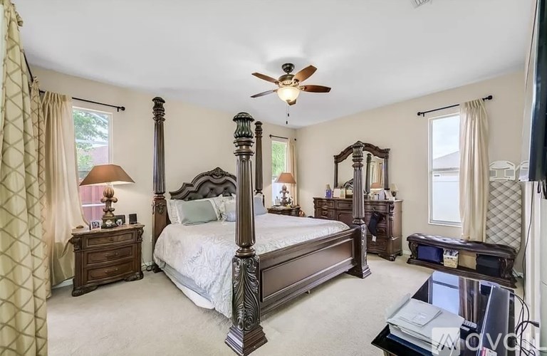A bedroom with a large bed and a ceiling fan.