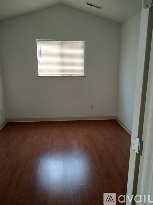 A room with wooden flooring and a window with blinds.