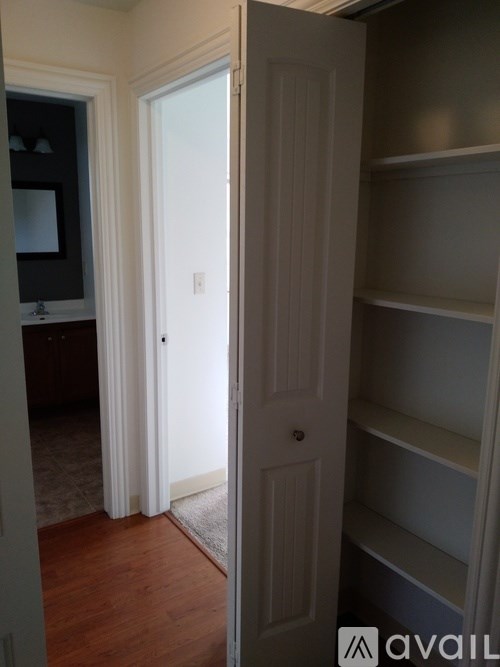 A white door is open to a room with a shelf.