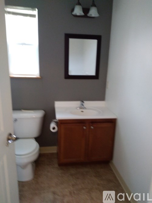 A bathroom with a toilet, sink and mirror.