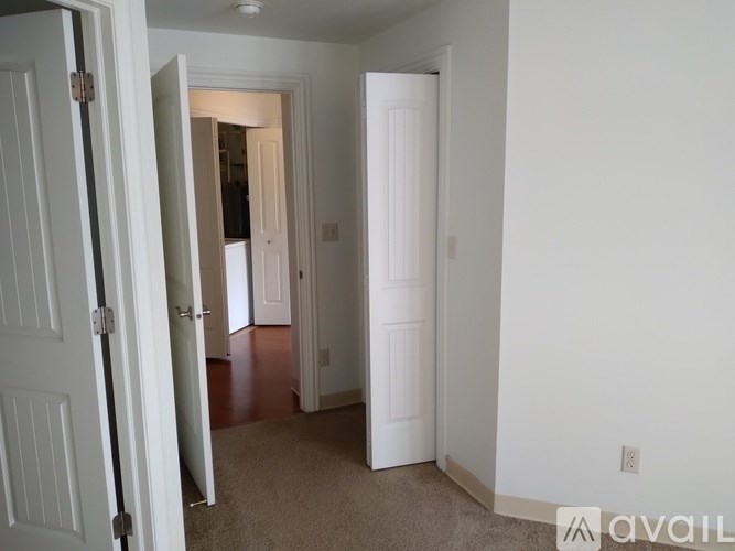 A hallway with a carpeted floor and white walls.
