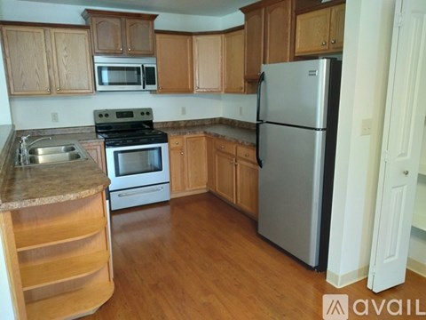 A kitchen with wooden cabinets and a stainless steel refrigerator.