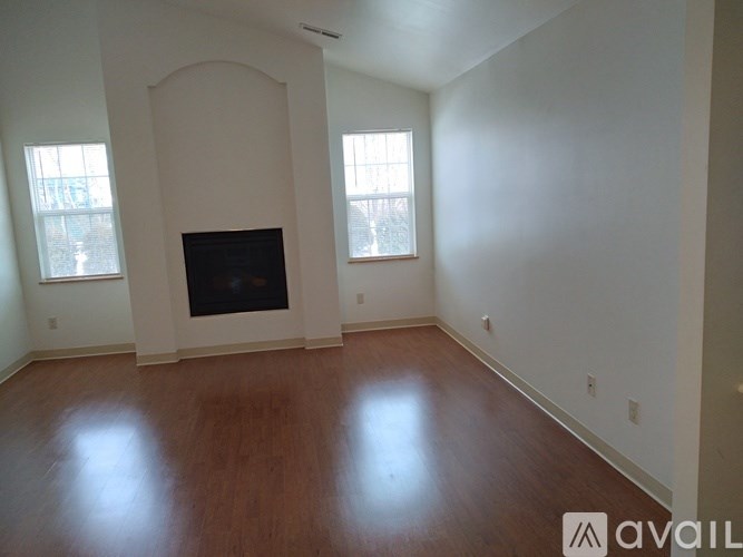 A living room with a fireplace and two windows.