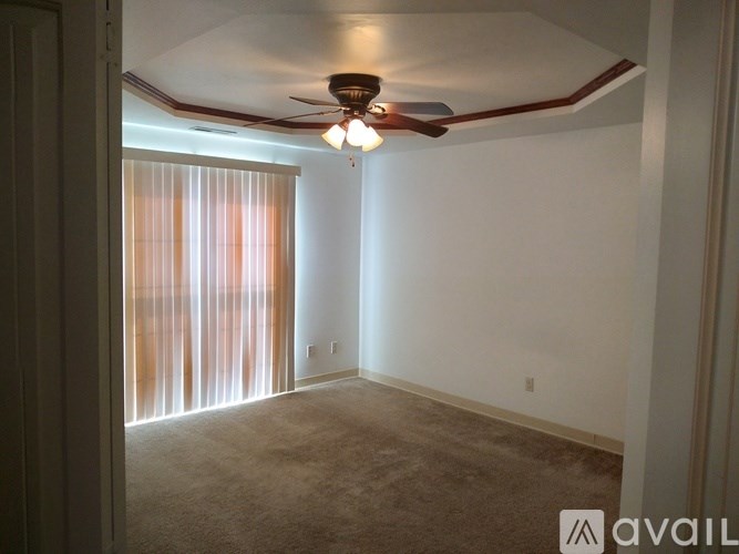 A room with a ceiling fan and a window with curtains.