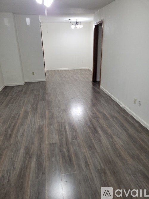 A room with wooden flooring and a door on the right side.