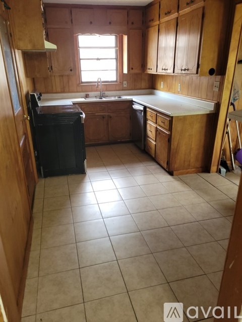 A kitchen with wooden cabinets and a black dishwasher.