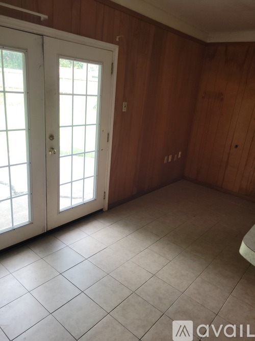 A room with a white door and wooden walls.
