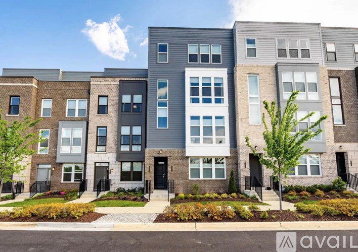 A row of modern townhouses with a clear blue sky above them.
