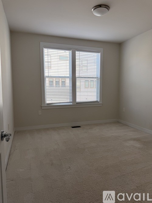 A room with a carpeted floor and a window with blinds.