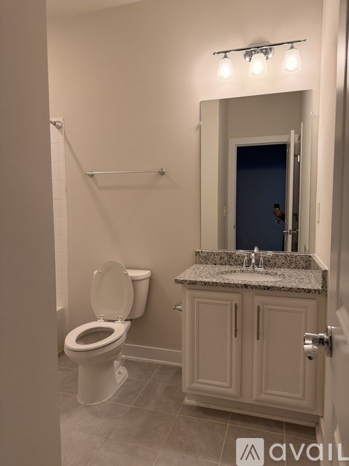 A bathroom with a toilet, sink, and mirror.