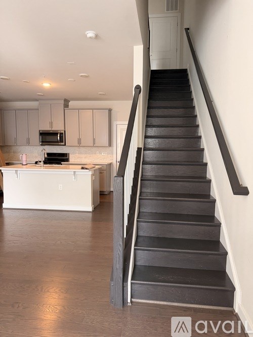 A staircase with a black railing and wooden steps leads up to a white door.