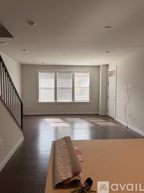 A room with a window and a table with a paper bag on it.