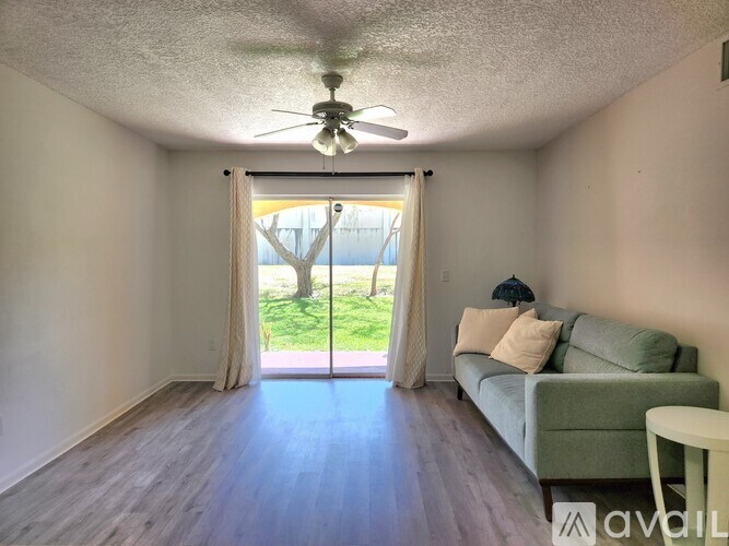 A living room with a couch, a ceiling fan, and a sliding glass door leading to a backyard.