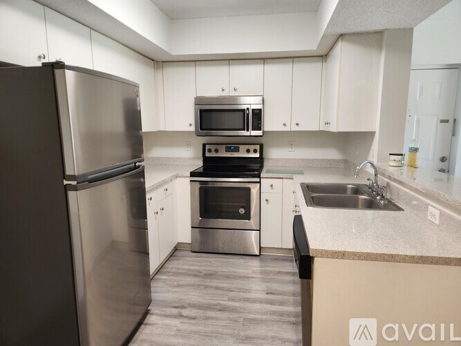 A kitchen with a black refrigerator and stainless steel appliances.