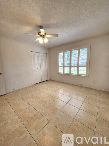 A room with a ceiling fan and a window with blinds.