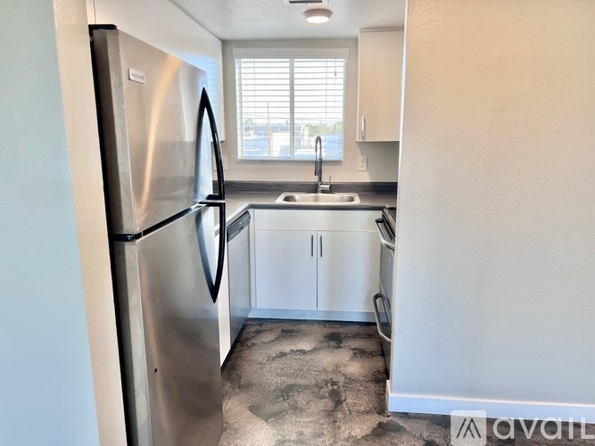 A kitchen with a stainless steel refrigerator and white cabinets.