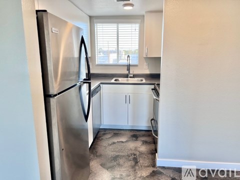 A kitchen with a stainless steel refrigerator and white cabinets.