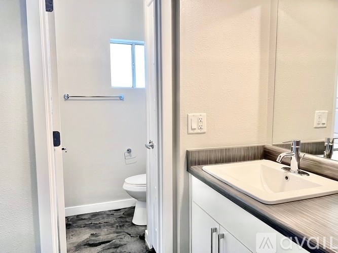 A bathroom with a toilet, sink, and mirror.