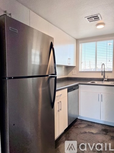 A kitchen with a stainless steel refrigerator and white cabinets.