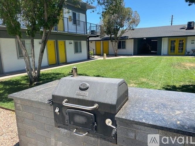 A brick oven is in the foreground of a grassy area with a building in the background.