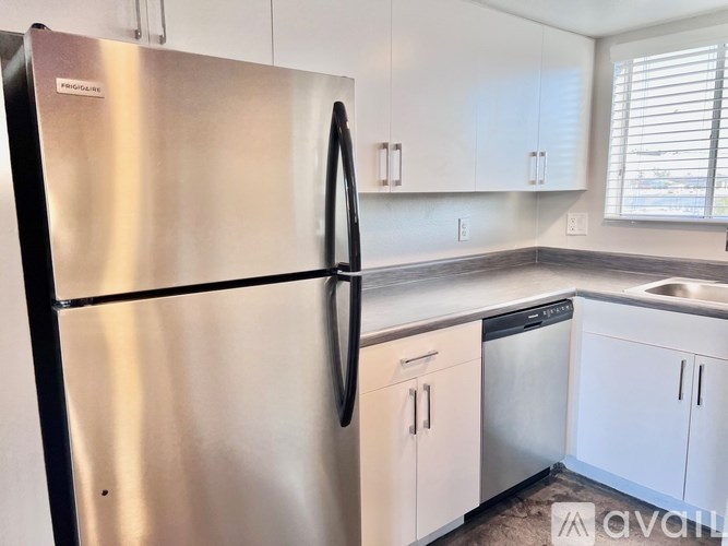 A stainless steel refrigerator with a black handle is in a kitchen with white cabinets.