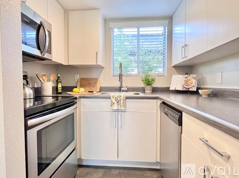A stainless steel refrigerator with a black handle is in a kitchen with white cabinets.
