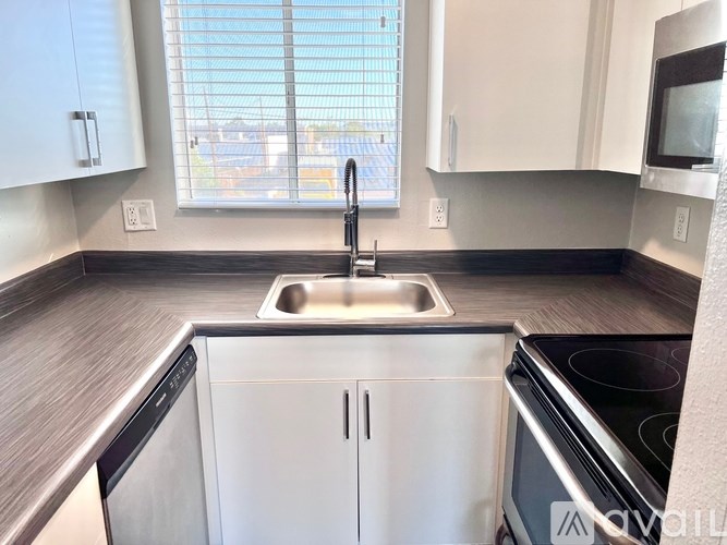 A kitchen with a stainless steel dishwasher and a white sink.