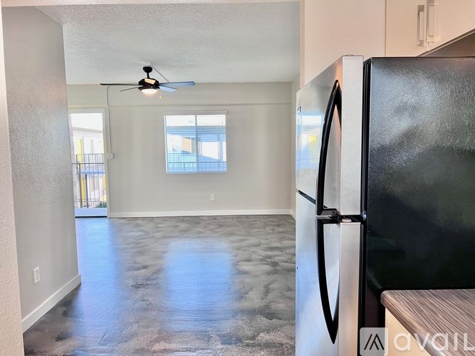A kitchen with a black fridge and a ceiling fan.