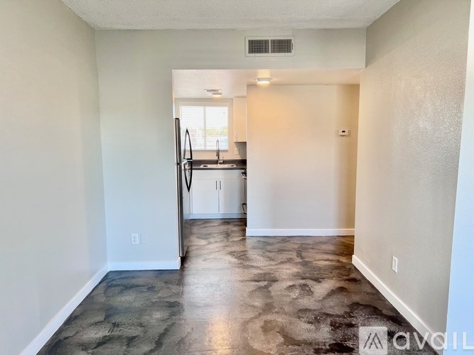 A kitchen with a refrigerator, sink, and cabinets is visible through an open door.