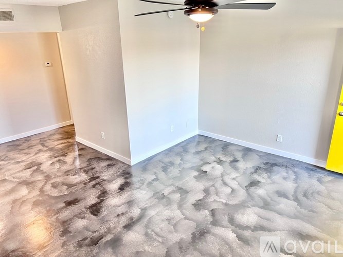 A room with a ceiling fan and a marbled floor.