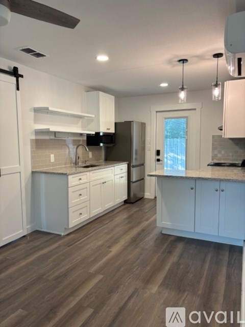 A kitchen with white cabinets and a wooden floor.