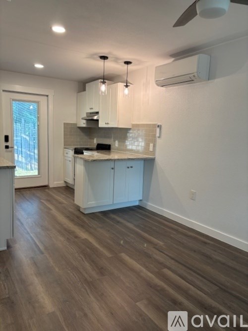 A kitchen with white cabinets and a wooden floor.