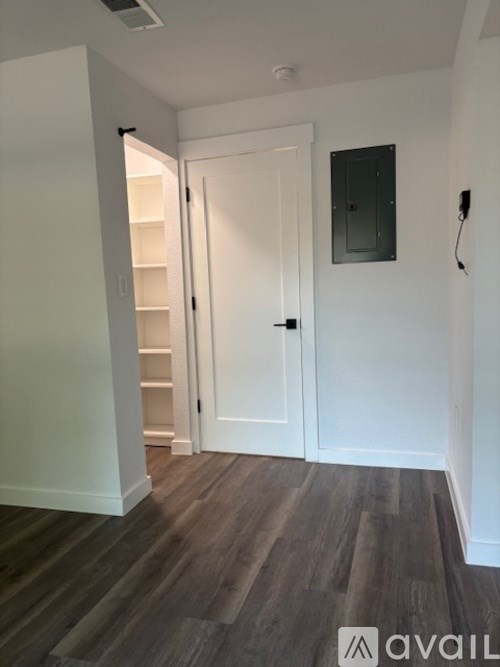 A room with a white door and a wooden floor.