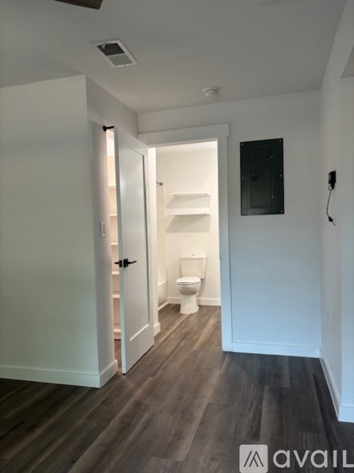 A bathroom with a toilet and a doorway leading to another room.