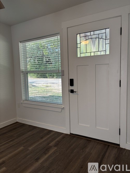 A white door with a window above it in a room with wooden flooring.