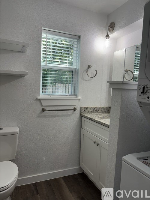 A small bathroom with a toilet, sink, and window.