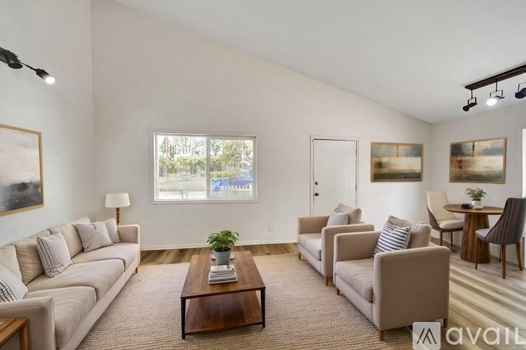 A living room with a large window, a sofa set, a coffee table, and a lamp.