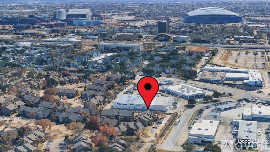 A red pin marks a location in a satellite image of a city.