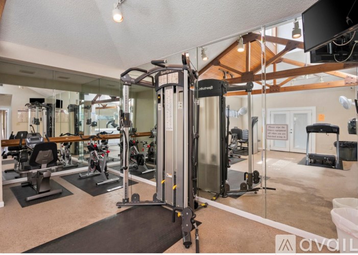 A gym with a mirrored wall and a variety of equipment.