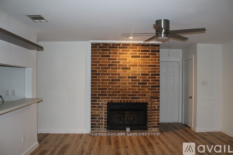 A room with a brick fireplace and a ceiling fan.