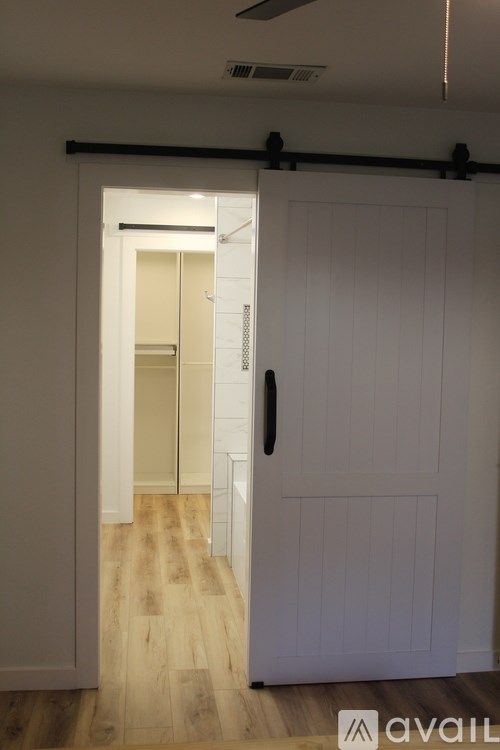 A white door with a black handle is open to a hallway.