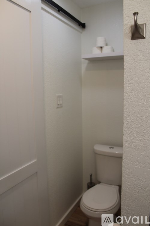 A white toilet in a small bathroom with a white door and a white wall.