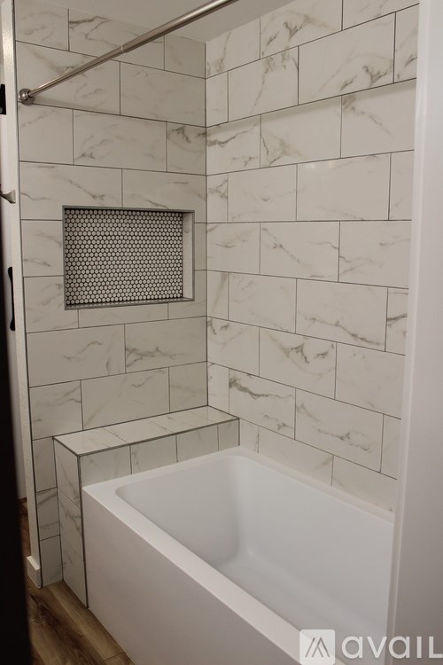 A white bathroom with a marble tile wall and a white tub.